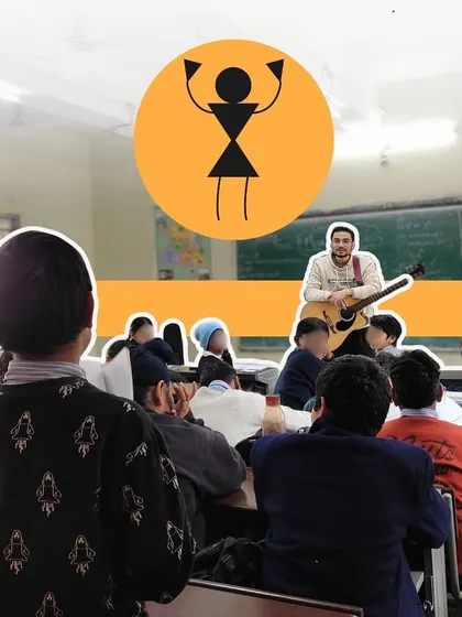 A fellow with a guitar engages a classroom of students. We believe that bringing live instruments into schools is key to sparking a genuine interest in music.