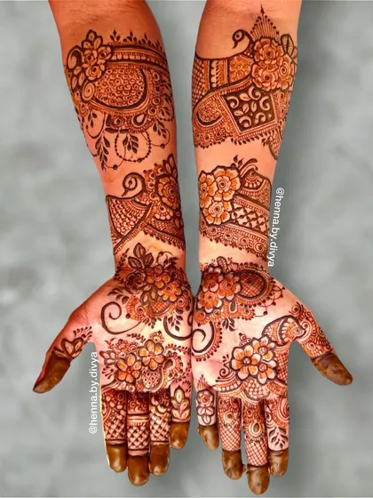 A beautiful full-sleeve bridal design with a mix of floral and traditional motifs. The palms are covered in dense flower patterns, while the arms feature peacocks and elephants.