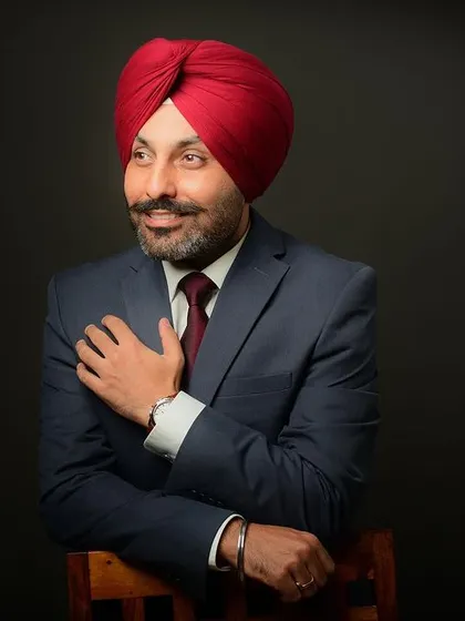 A distinguished portrait of a professional in a suit and turban. The lighting is crafted to highlight his features and convey a sense of wisdom and experience.