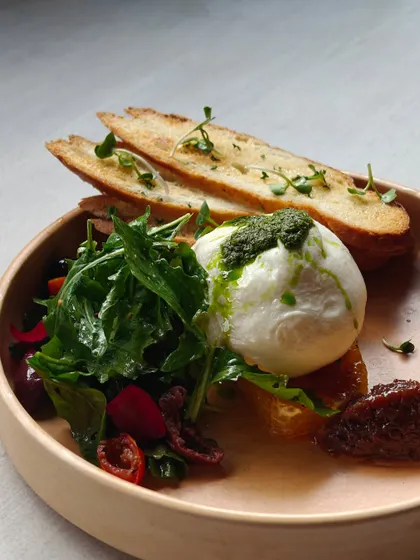 Fresh burrata served with an arugula salad, sun-dried tomatoes, and pesto, accompanied by toasted bread. Simple, fresh, and full of flavor.