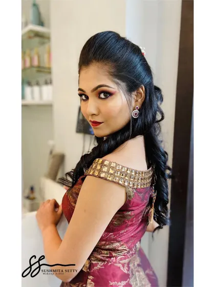 This side profile highlights the elegant hairstyle with soft curls and a puffed crown, which complements the glamorous makeup for a chic and polished Sangeet look.