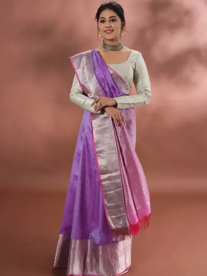A model wearing a beautiful purple saree with a silver zari border. This piece showcases how our traditional weaves can be styled for a contemporary and elegant look.