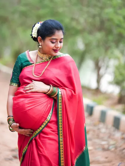 A beautiful outdoor portrait of a mom-to-be in a traditional red saree.
