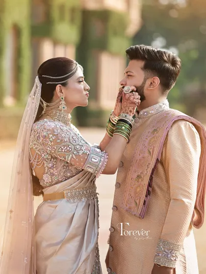 A playful and romantic moment. The groom wears a custom pastel sherwani with a matching dhoti, a modern fusion look that is both elegant and comfortable for a pre-wedding photoshoot.