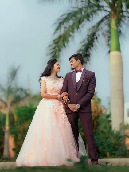 A classic couple portrait in a garden setting. The bride's soft pink ball gown with 3D floral details is the epitome of romance and grace.