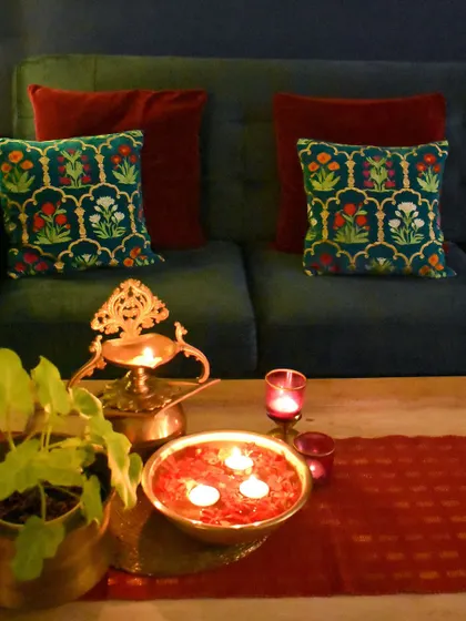 A close-up of the festive details. The traditional brass diya and a bowl of floating candles on the coffee table add a simple yet elegant touch.