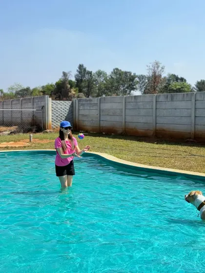 An owner joins her dog in the pool for a game of fetch, making it a fun and interactive experience for everyone.