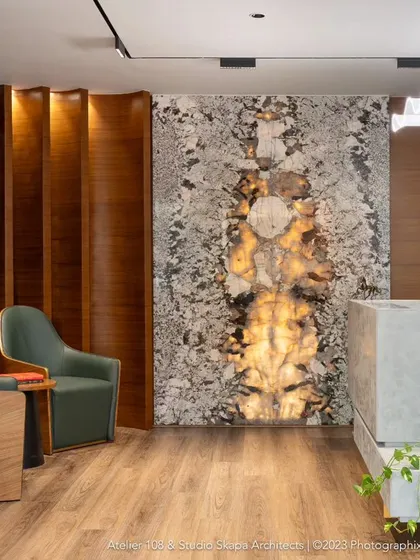 The extravagant lobby of Meghana Foods' corporate office, featuring a backlit onyx wall as the centerpiece. This space was designed to be opulent yet inviting, using plush furnishings and rich wood tones to welcome visitors.
