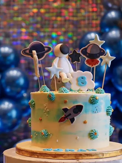 The cake for the outer space themed party, complete with an astronaut, planets, and stars. Every detail is considered to make the theme cohesive.
