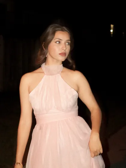 Modeling a dreamy pink halter-neck tulle dress from Jardinvue in a moody, nighttime shot.