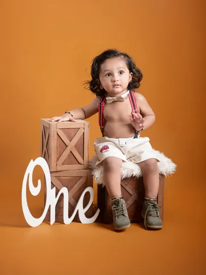 This portrait from a "One" themed session showcases the baby's sweet and curious nature. The simple props and warm lighting keep the focus entirely on him.