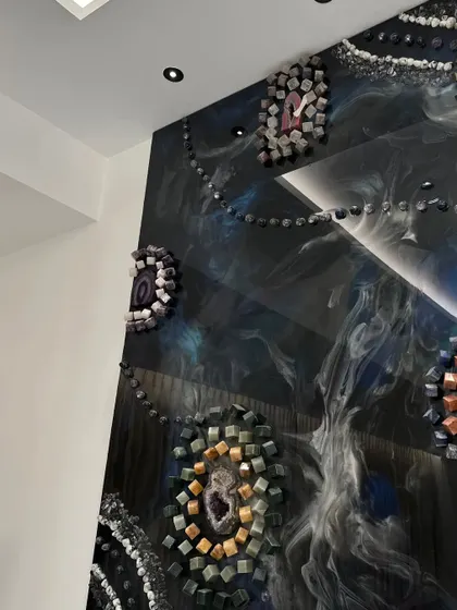This photo shows the top section of the 10x6 feet conceptual wall art, where the natural stones and geodes are set against a swirling galaxy-like resin background.