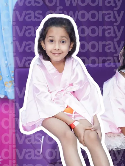 A happy smile from a young guest enjoying the 'Divas of Wooray' experience. Dressed in a soft pink robe, she's ready for a day of fun, friendship, and feeling special.