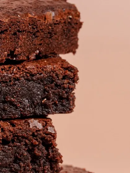A close-up of our warm, fresh-baked brownies. They are perfectly gooey, fudgy, and decadent, designed to melt in your mouth.