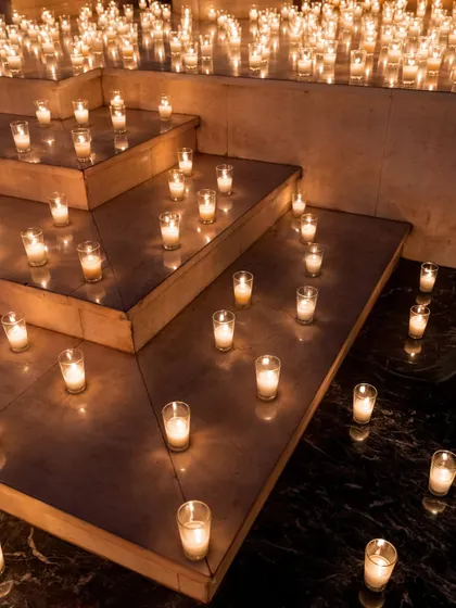 Steps covered in a dense arrangement of glass candles, creating a pathway of light.