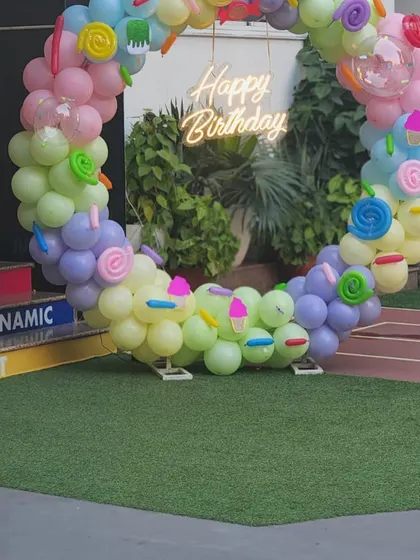 A circular balloon wreath with a neon sign is a modern and fun photo backdrop. The candy and ice cream details in the balloons tie the whole theme together.