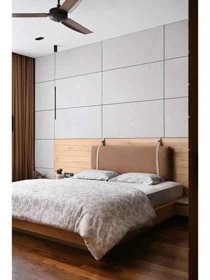 The son's bedroom combines hardwood flooring with a feature wall of large concrete panels. The custom headboard with leather cushions adds a touch of softness and sophistication.