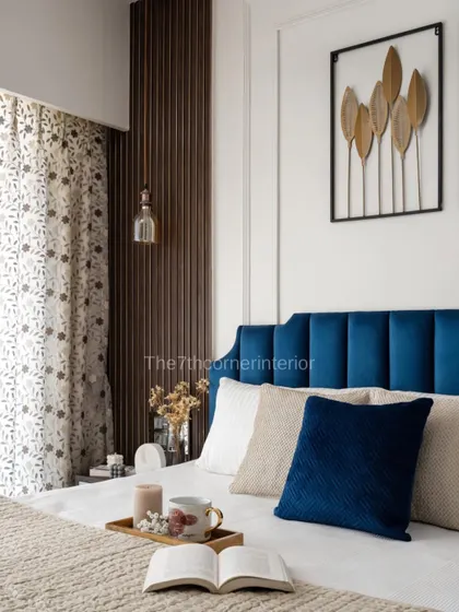 A close-up view of the luxurious bedroom from 'The Adobe' project. The combination of the velvet headboard, patterned curtains, and warm pendant light creates a cozy and inviting atmosphere.