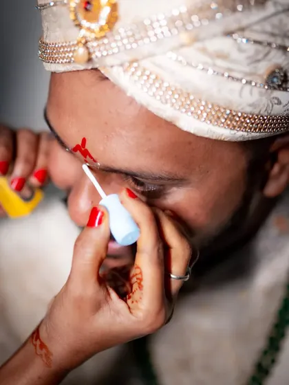 A close-up shot of the groom's tilak being applied, a significant and detailed moment from the wedding preparations.