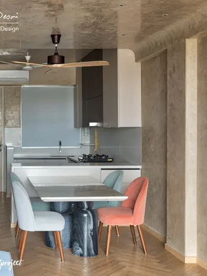 Another view of the open-plan kitchen and dining space in the "RED Fort Project." The herringbone wood flooring and textured walls add warmth and character to the modern layout.