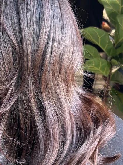 A close-up on the mocha-toned curls, showing the dimension and depth of the color against the salon's greenery.