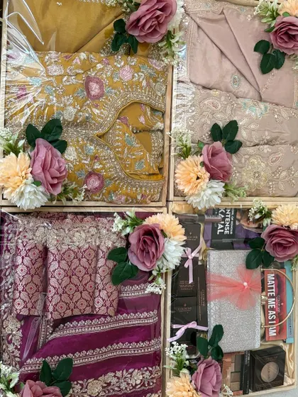 A mix of traditional and modern gifts for a wedding. This collection includes beautifully packed sarees alongside a hamper of contemporary cosmetics, showing our versatility in trousseau curation.