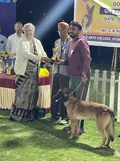 A Belgian Malinois and his handler accepting a trophy for their hard work.