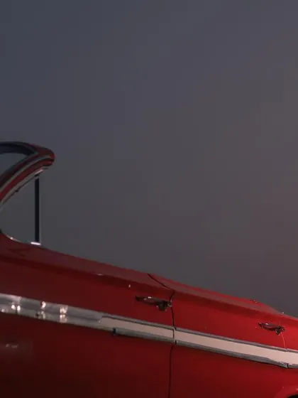 An intimate and romantic shot of the couple in a classic red car at night, creating a private and cinematic moment.