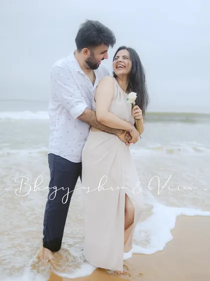 A playful and happy pre-wedding portrait on a Goa beach. The couple is laughing, surrounded by the gentle waves.