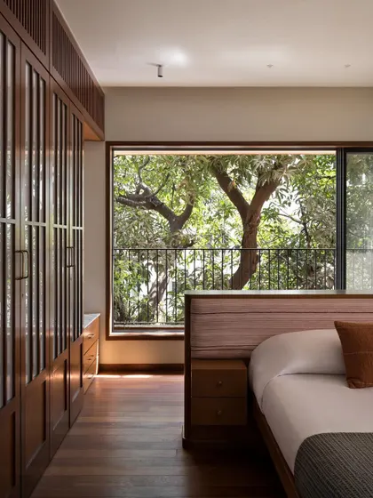 The design of this bedroom is all about framing the view. The window acts like a living painting, bringing the beauty of the mature trees directly into this private sanctuary.