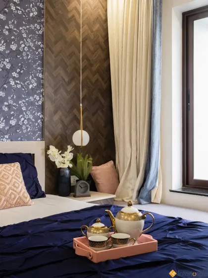 This detail shot shows the layered design next to the bed, with a floral wallpaper accent panel, a dark wood herringbone panel, and a modern hanging globe light.