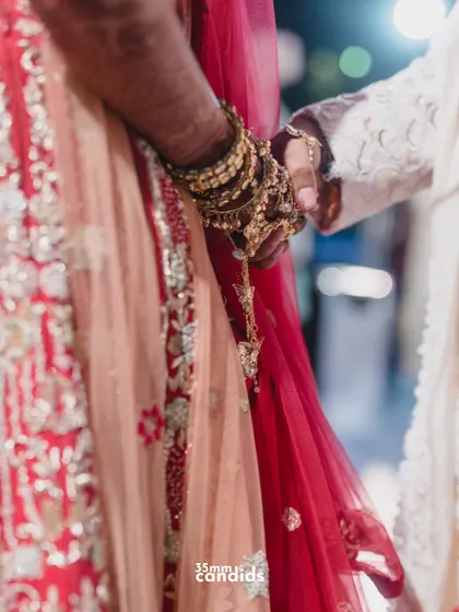 A close-up of the bride and groom's hands clasped during the ceremony, her intricate kaleere dangling. This shot captures the blend of tradition and personal connection.