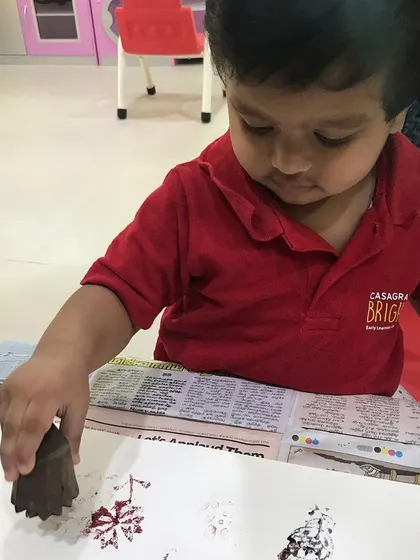A young child carefully presses a wooden block onto paper during one of our workshops. We love introducing even the littlest artists to the joy of block printing with natural, non-toxic inks.