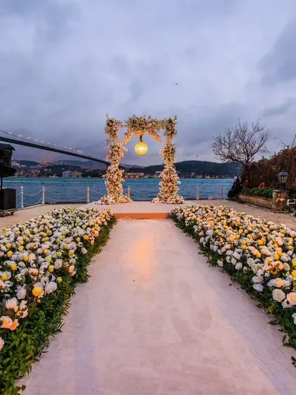 A beautiful wedding aisle lined with white and yellow roses, leading to a floral arch overlooking the Bosphorus in Istanbul. A perfect blend of natural beauty and elegant design.
