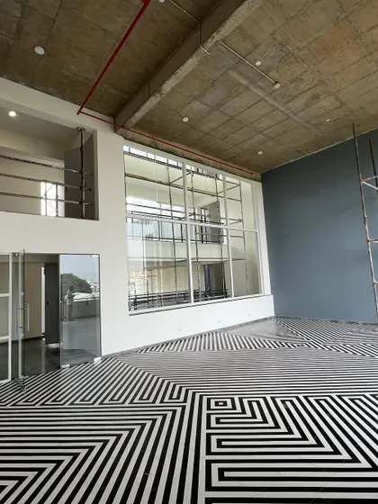 The social core of 'The Treehouse' apartments features a double-height lounge with a striking black and white geometric floor pattern. This space serves as a central hub, visually and functionally connecting different amenities and residential floors.
