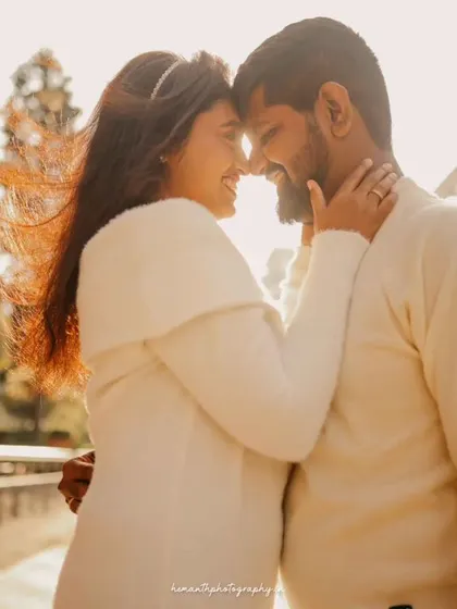 A romantic, sun-flared shot of a couple about to kiss, set against a modern city backdrop during the golden hour.