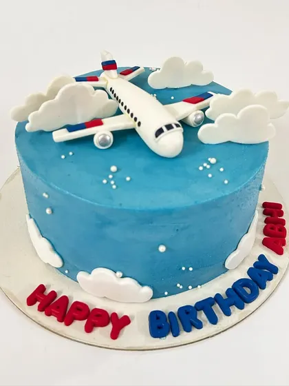 A sky-high adventure! This airplane-themed cake features a fondant plane soaring through fluffy buttercream clouds.
