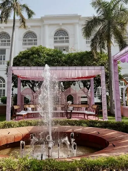 A wide view of the beautiful garden Mehendi setup, with the venue's fountain as a central feature, surrounded by pastel canopies and elegant seating.