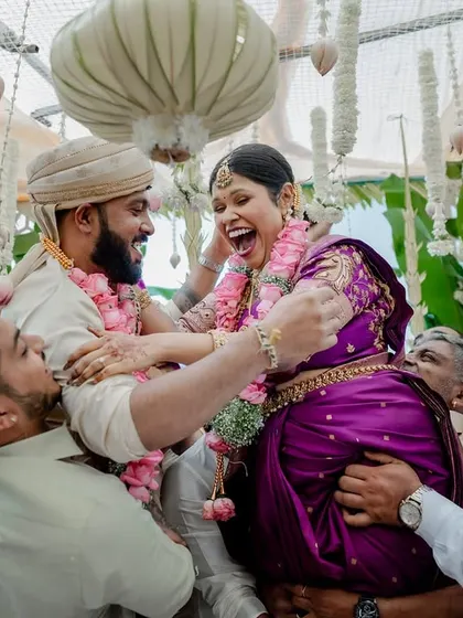 The fun and games of wedding rituals. This moment of laughter during a post-wedding game shows the playful spirit and strong bond between the couple and their families.