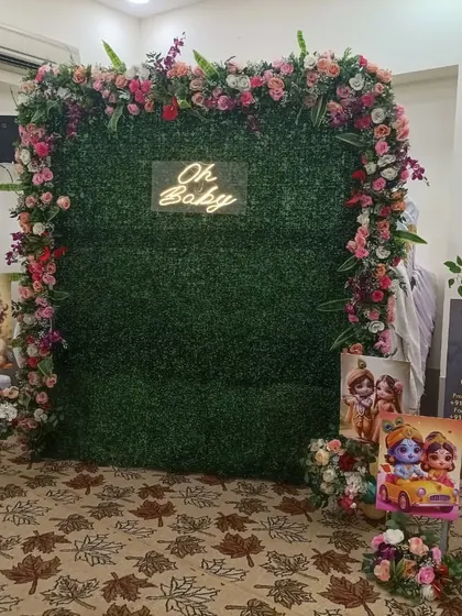 A greenery wall is a great option for a photo booth. Here, I decorated a boxwood panel with a floral border and an 'Oh Baby' neon sign, perfect for guest photos.