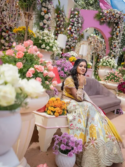 The bride is seated amidst an explosion of flowers. This shot highlights the sheer volume and artistry of the floral arrangements, creating an immersive and luxurious atmosphere.