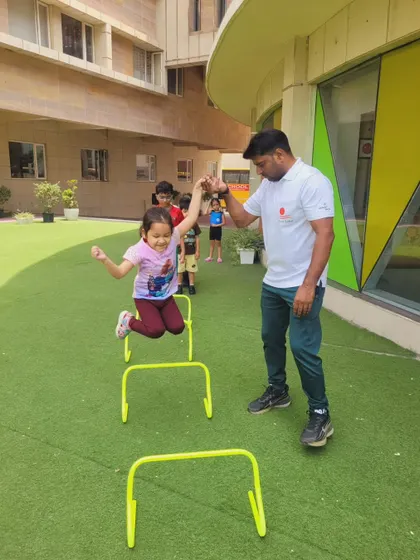 An instructor offers a helping hand as a camper navigates the hurdle course. This supportive environment ensures that children of all skill levels can participate fully and safely.