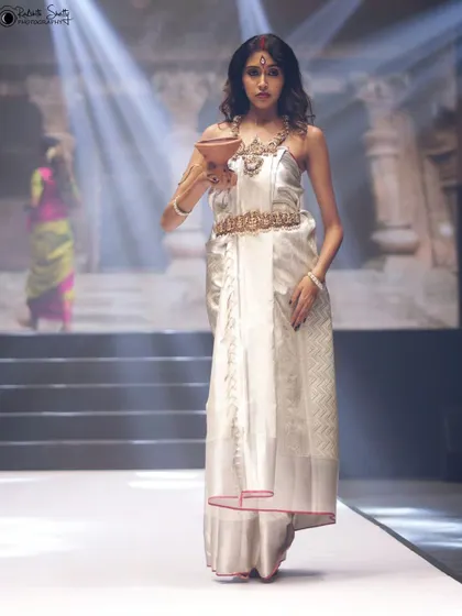 A full-length view of the model in the white saree, showing her confident walk down the runway. This shot captures the entire look, from the detailed top to the elegant drape of the fabric.