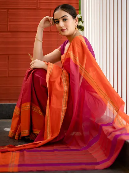 A lovely portrait in a vibrant pink and orange saree. The seated pose is relaxed and natural, and the colors of the saree pop against the background.