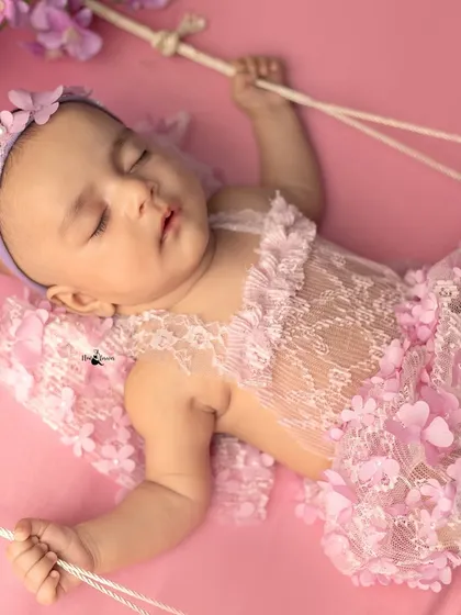 A different angle of the fairy swing pose, showing the baby sleeping soundly while gently holding the ropes. Every detail is arranged to create a magical scene.