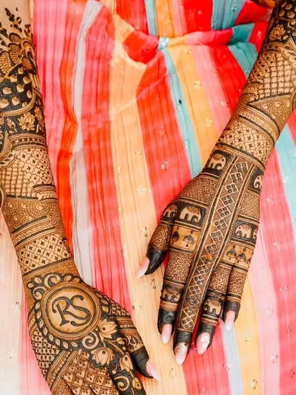 A beautiful back-hand design featuring the couple's initials 'RS' in a circle. The design is complemented by elephant motifs and traditional patterns.