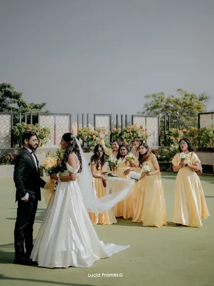 A fun, candid moment between the bride, groom, and bridesmaids, with the veil caught in the wind.