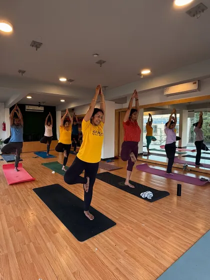 A group of students holds Vrikshasana (Tree Pose) together. There's a special energy when we find our balance as a community.