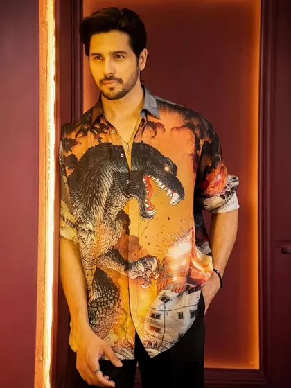 A close-up portrait of Sidharth Malhotra. The warm tones of the shirt and the background create a cohesive and visually appealing image for this promotional shoot.