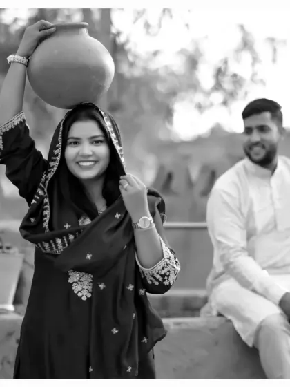 Another shot from the village-themed pre-wedding session. The bride playfully carries a pot on her head, adding a touch of traditional charm and authenticity to their love story.